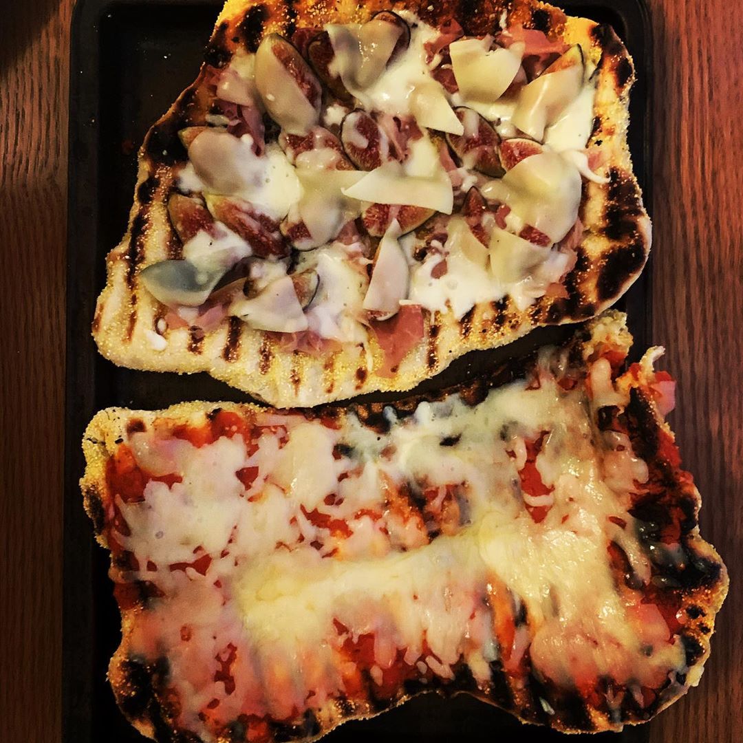 Two oblong pizzas on a cookie sheet on a wood table