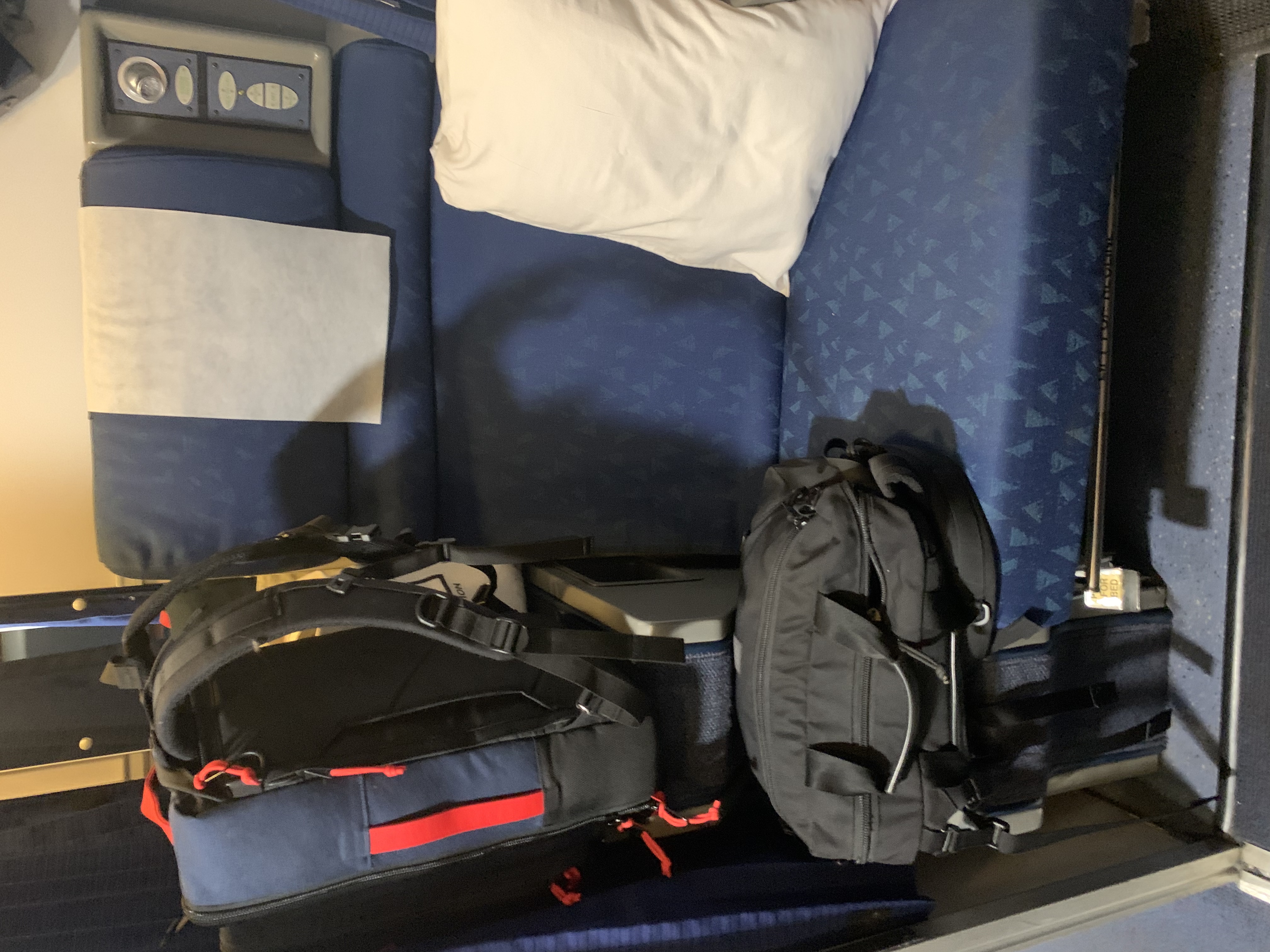 Picture of an Amtrak Superliner Roomette, with two seats facing each other and some luggage